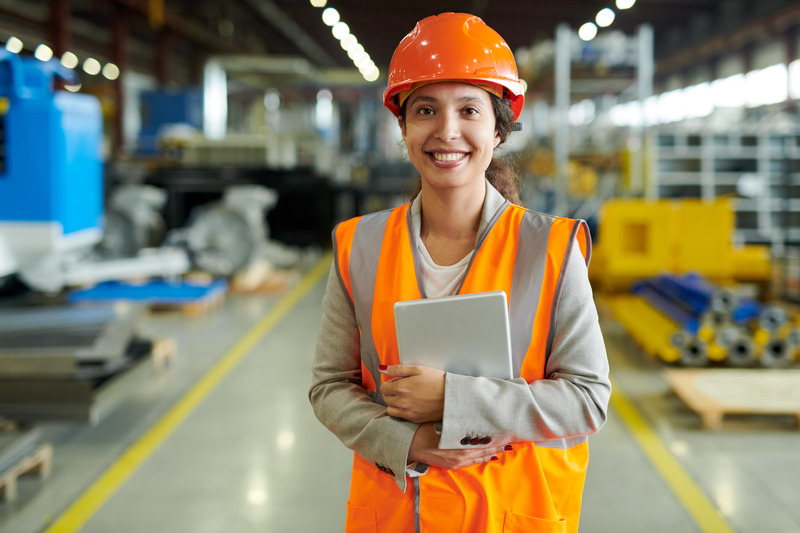 Opératrice casquée sur un site industriel, tablette à la main
