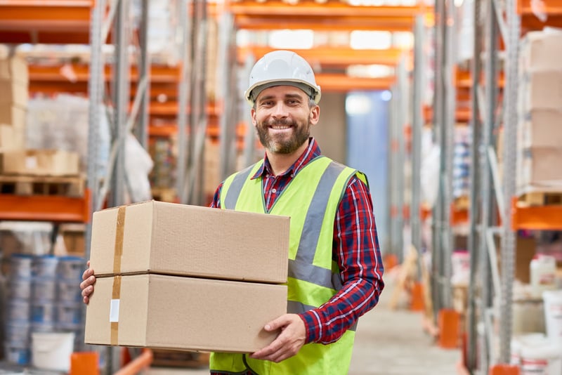 Manutentionnaire portant deux cartons dans un entrepôt